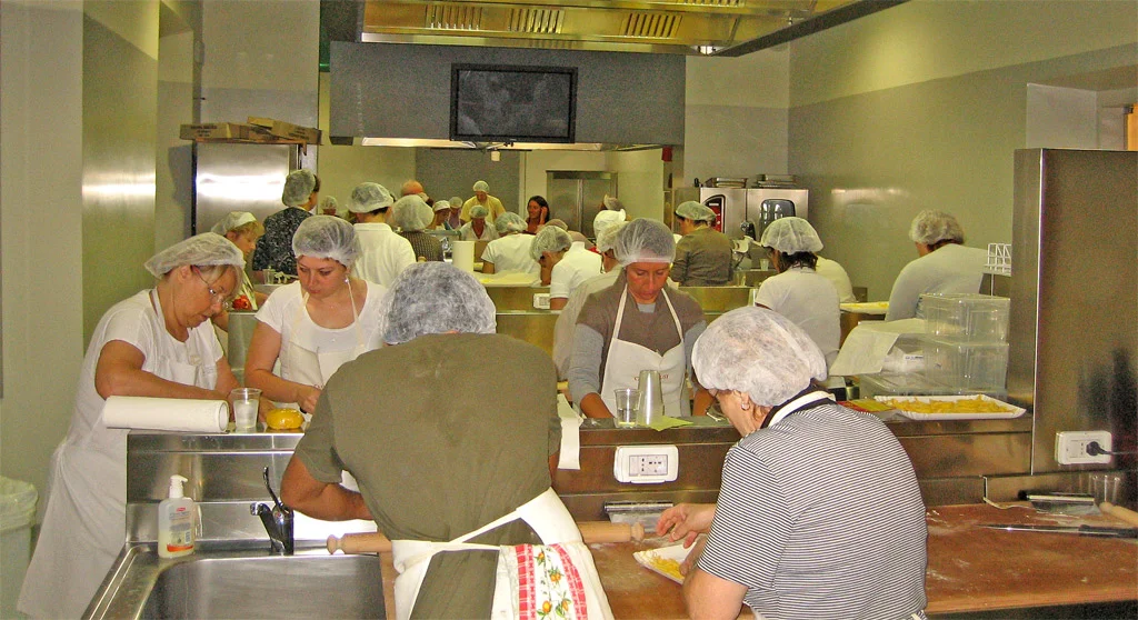 Persone impegnate in un corso di cucina in una sala di Casa Artusi